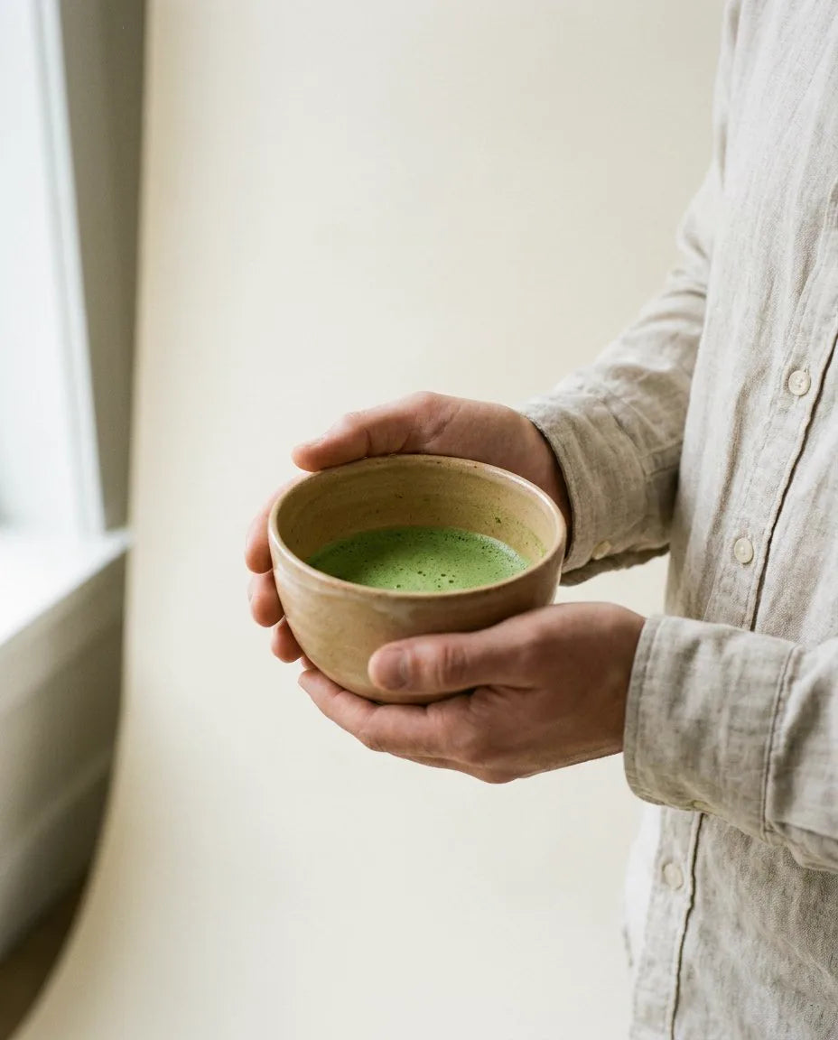 Manos sosteniendo un chawan de matcha batido