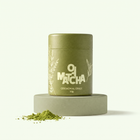 Lata de Oji Matcha ceremonial 30g sobre pedestal verde salvia con polvo de matcha